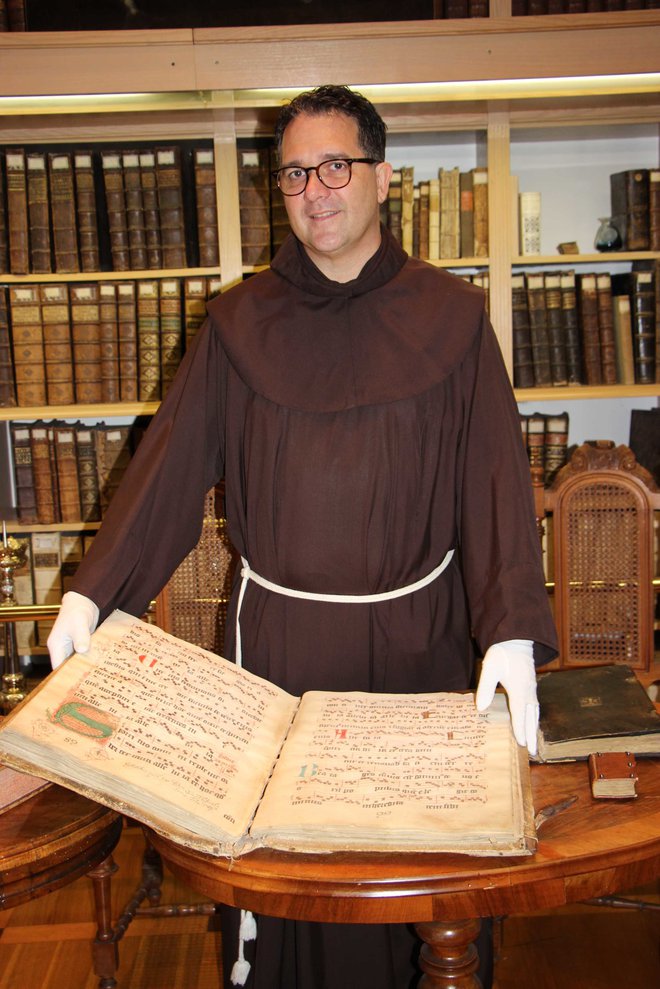 Gvardijan p. Tomaž Hočevar z najstarejšo knjigo iz leta 1418, ki so jo frančiškani prinesli iz Bosne. Foto Tanja Jakše Gazvoda