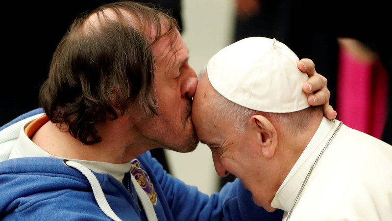 Fotografija: Na papeževi tedenski avdienci v Vatikanu je eden od vernikov poljubil svetega očeta na čelo. FOTO: Yara Nardi/Reuters