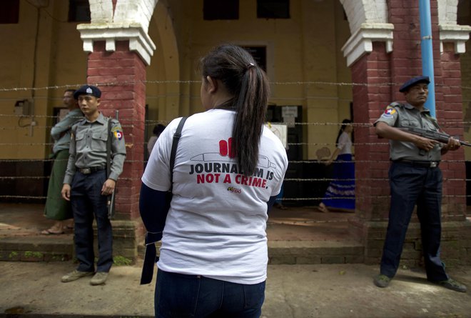 Novinarka z napisom na majici "novinarstvo ni zločin" stoji zunaj sodišča, kjer so sodili dvema novinarjama.  FOTO: Thein Zaw/AP