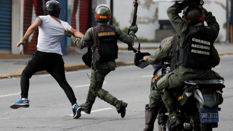 Fotografija: Pripadniki venezuelskih varnostnih sil lovijo protestnika med januarskimi protivladnimi demonstracijami v Caracasu, med katerimi je bilo pridržanih 740 ljudi. FOTO: Reuters