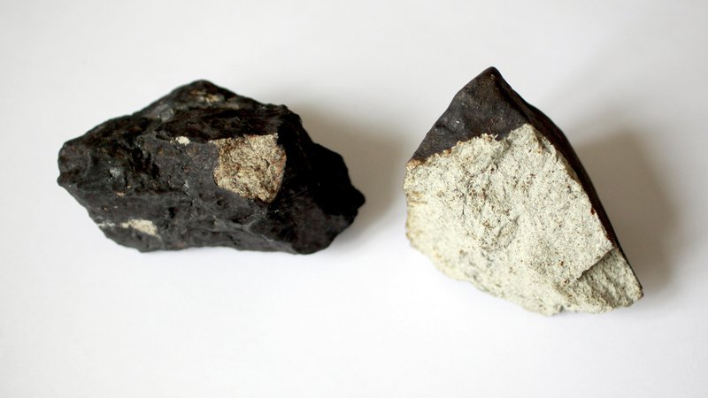 Fotografija: Primerek meteorita z Jesenic. Za meteorite je značilna temna zunanjost in svetla notranjost. FOTO: Roman Šipić/Delo