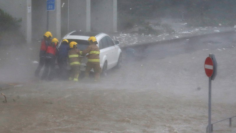 Fotografija: Gasilci pomagajo v poplavah ujetemu vozniku. FOTO: Bobby Yip/Reuters