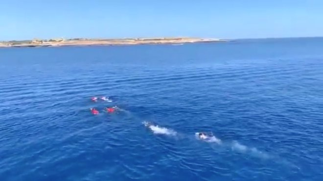 Pet migrantov je z ladje skočilo v morje in začelo plavati proti obali Lampeduse, a so jih vrnili na ladjo. FOTO: Reuters