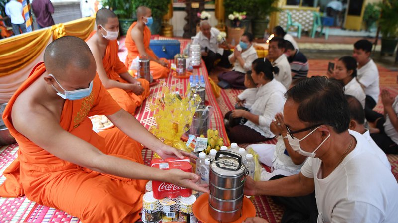 Fotografija: V pagodi v Phnom Penhu menihi sprejemajo hrano. FOTO: Tang Chhin Sothy/AFP