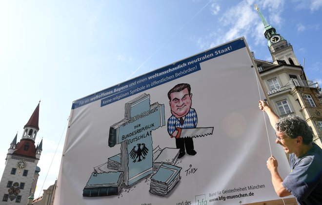 Moški proti odloku protestira s plakatom karikature Marka Söderja. FOTO: Christof Stache/AFP