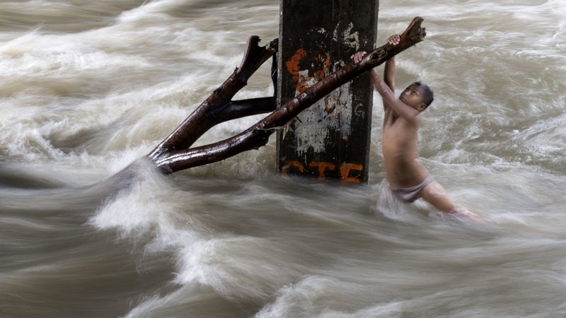 Fotografija: Po hudem nalivu so reke v Manili precej narasle, kar pa otrok ni odvrnilo od igranja in kopanja v njej. FOTO: Noel Celis/AFP