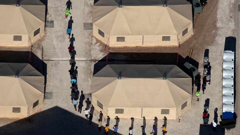 Fotografija: V objektu za pridržanje ob mehiški meji v teksaškem mestu Tornillo osebje vodi otroke priseljencev med šotori do prostora, v katerem strežejo hrano. FOTO: Mike Blake/Reuters