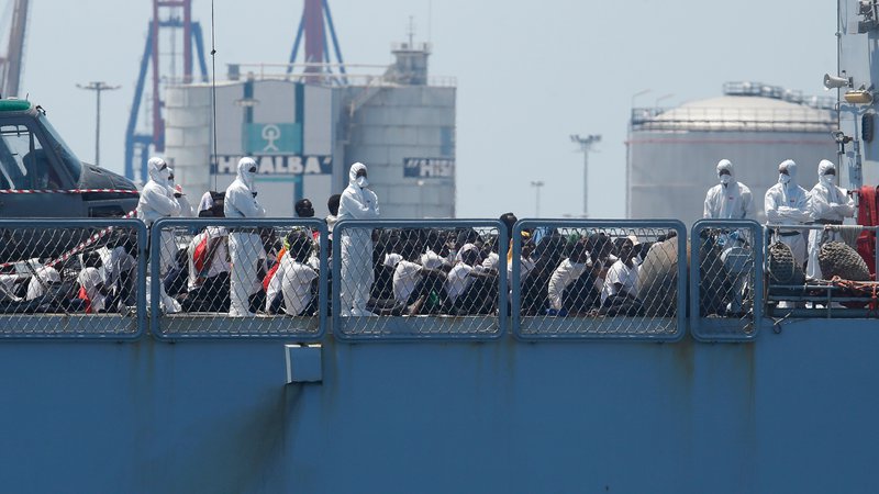 Fotografija: TOPSHOT - Migrants sit on the deck of the Italian navy ship Orione as the ship enters the port of Valencia on June 17, 2018. 
The Aquarius rescue ship with more than 600 people on board, has been the heart of a major migration row between European Union member states.  / AFP PHOTO / PAU BARRENA