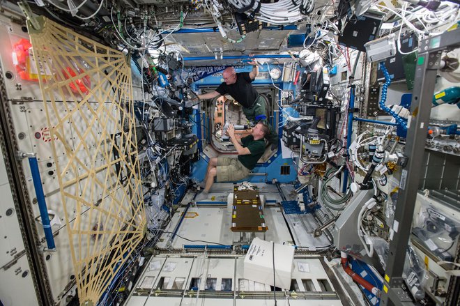 Terry Virts (spodaj) in Scott Kelly (zgoraj) se pripravljata na pregled vida v laboratoriju Destiny; znanstveniki morajo proučiti morebitni vpliv dolgih vesoljskih potovanj na vid astronavtov, preden jih pošljejo na misije daleč od Zemlje – na aster