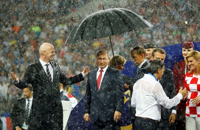 Dež je namočil vse politike, samo Putin je imel vseskozi dežnik. FOTO: Reuters