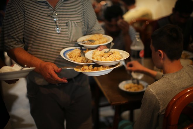 Begunci in migranti v nekdanji restavraciji, kjer jim prostovoljci pripravljajo tople obroke. FOTO: Jure Eržen