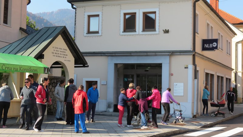 Fotografija: Pred bančno poslovalnico v Črni se zgrinjajo domačini. Prišli so tudi komitenti iz Centra za usposabljanje, delo in varstvo. FOTO:  Mateja Kotnik 