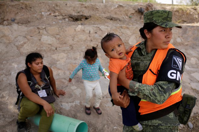 Članica ameriške Nacionalne garde na mehiški meji s Teksasom drži honduraškega otroka, ki je lani z materjo in sestrico ilegalno vstopl v ZDA. FOTO: José Luis Gonzalez/Reuters