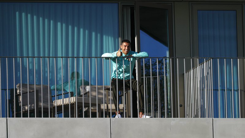 Fotografija: Cristiano Ronaldo je po razkritju, da je okužen z visrusom sars-cov-2 z balkona hotelske sobe v kampu portugalske nogometne reprezentance pošiljal pozdrave in nasmehe, včeraj pa je že s posebnim letalom dopotoval v Torino, kjer bo do konca izpeljal osamitev. FOTO: Diogo Pinto/AFP
