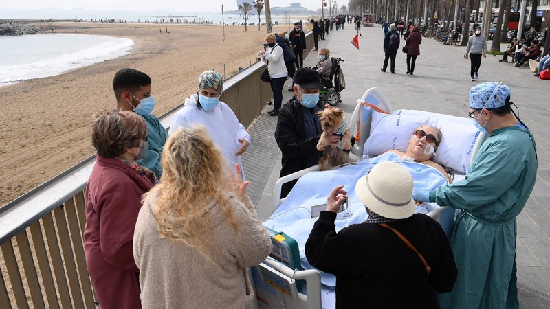 Fotografija: Prijatelji, sosedje in zdravstveno osebje obkrožajo 72-letno bolnico s COVID-19 Marto Pascual, ko je na plaži Barceloneta, ki se nahaja v neposredni bližini bolnice del Mar v Barceloni dobila svež zrak. FOTO: Lluis Gene/Afp