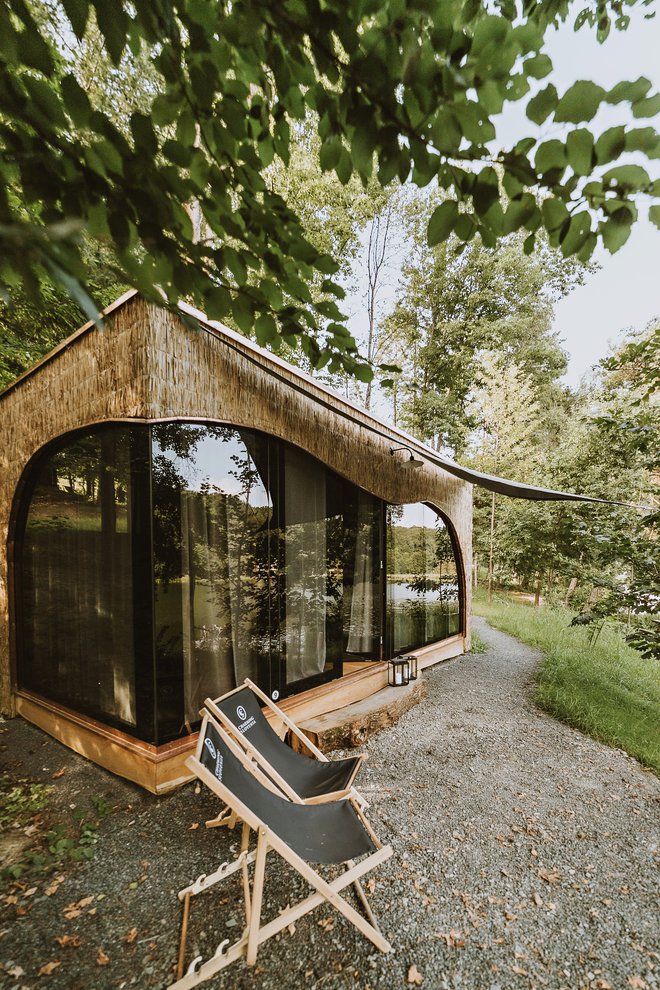 Hiške se s svojimi oblikami in materiali zlijejo z okoljem gozda ob jezeru. FOTO: Charming Slovenia
