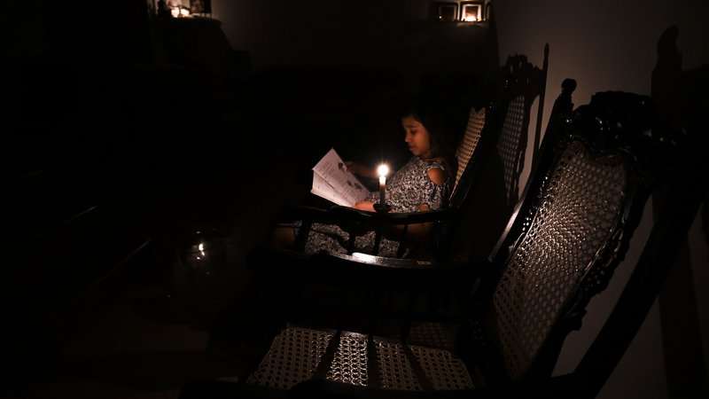 Fotografija: S pomanjkanjem dobave električnega toka se sooča več azijskih držav. Na fotografiji dekle iz Šrilanke, ki bere knjigo ob sveči; oblasti so namreč prilagodile porabo električne energije. FOTO: Ishara S. Kodikara/Afp