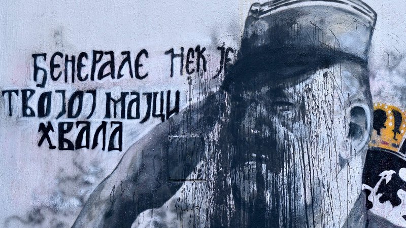 Fotografija: Slika obsojenega vojnega zločinca Ratka Mladića na steni ene od stavb v Beogradu je bila predmet spora med zanikovalci genocida in meščani, ki menijo, da zanikanje genocida v sodobno evropsko državo ne sodi. Foto Andrej Isakovic Afp
