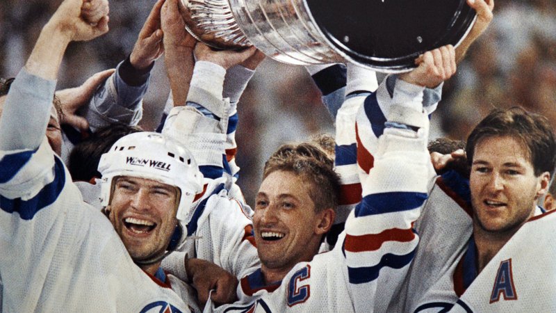 Fotografija: Wayne Gretzky s Stanleyjevim pokalom, ki ga je leta 1988 v Edmontonu osvojil ob boku Marka Messierja (levo) in Kevina Lowa (desno). FOTO: Mike Blake/Reuters
