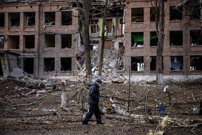 Moški hodi pred uničeno stavbo po ruskem raketnem napadu v mestu Vasilkov blizu Kijeva. FOTO: Dimitar Dilkoff/AFP
