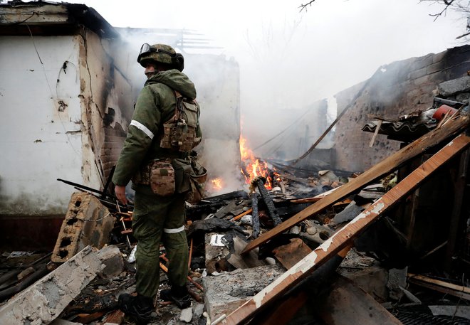 Separatistični vojak v Donecku ob hiši, ki jo je uničilo obstreljevanje ukrajinske vojske. FOTO: Alexander Ermochenko/Reuters
