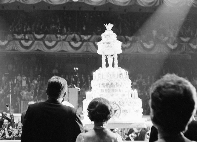Po prihodu velikanske torte na oder je John F. Kennedy množico nagovoril z besedami: »Zdaj ko sem dobil tako zapeljivo rojstnodnevno čestitko, se lahko umaknem iz politike!« FOTO: Cecil Stoughton. White House Photographs. John F. Kennedy Presidential Library And Museum, Boston
