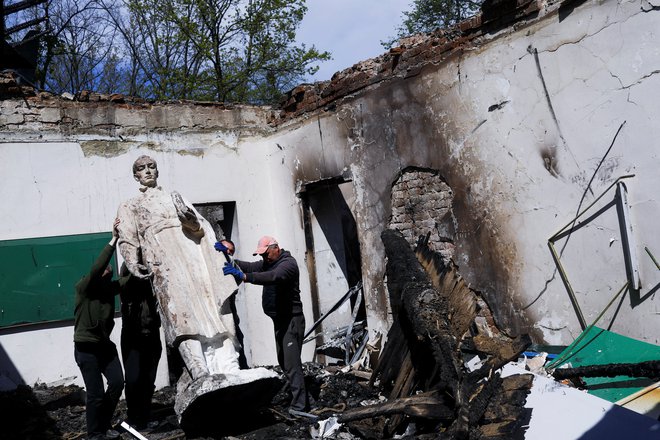 Zaposleni odstranjuje kip ukrajinskega filozofa Grigorija Skovorode po ruskem napadu na spominski muzej, posvečen temu filozofu v vasi Skovorodinivka blizu Harkova. FOTO: Ricardo Moraes/Reuters
