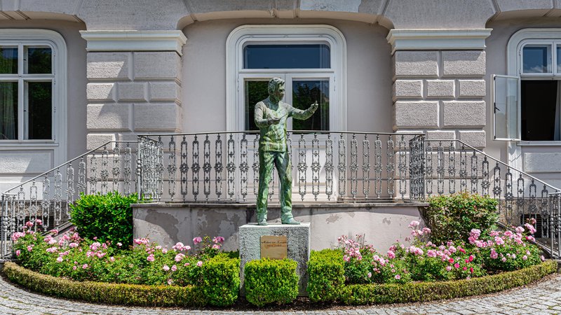 Fotografija: Kip dirigenta Herberta von Karajana obiskovalce pozdravlja z vrta njegove rojstne hiše, od koder se odpira lep pogled na Salzburg. FOTO: Shutterstock
