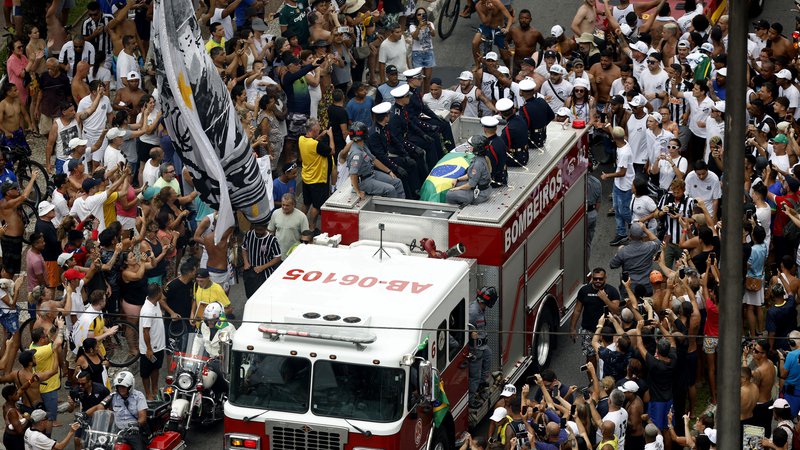 Fotografija: Pelejevo krsto, ki so jo prekrili z zastavama Santosa in Brazilije, so s stadiona odpeljali na gasilskem tovornjaku. FOTO: Amanda Perobelli /Reuters
