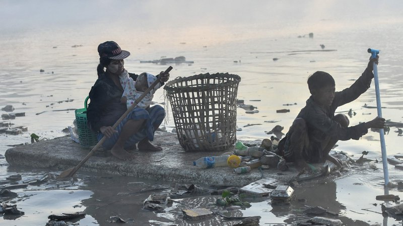 Fotografija: Zbiralci odpadkov s čolni iz polistirena iščejo plastiko in steklo za recikliranje v reki Pazundaung v Jangonu.  Na desetine burmarskih zbiralcev odpadkov se je podalo v mračne vode reke v Jangonu, potem ko jih je gospodarska kriza po državnem udaru prignala do iskanja dela. Foto: Sai Aung Main/Afp
