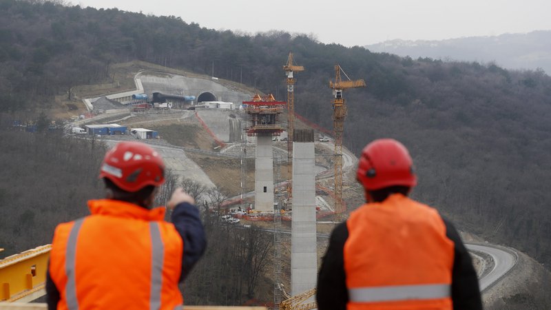 Fotografija: Nekaj sto metrov stran druga ekipa več deset metrov nad tlemi na že končanem stebru pripravlja vse potrebno za nadaljevanje gradnje viadukta. FOTO: Leon Vidic/Delo
