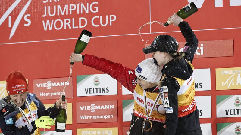 Fotografija: Katharina Althaus (levo), Eva Pinkelnig (v sredini) in Ema Klinec so razglasitev najboljših v seštevku svetovnega pokala začinile s šampanjcem. FOTO: Antti Hämäläinen/AFP
