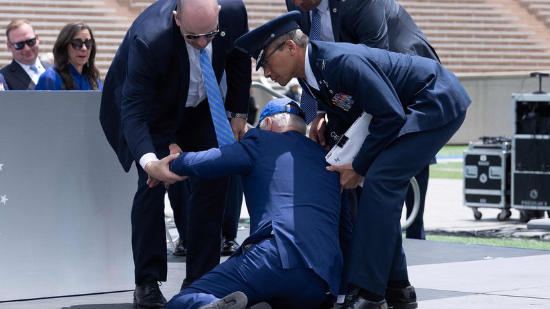 Fotografija: Na noge so mu pomagali pripadnik zračnih sil in dva člana njegove tajne službe. FOTO: Brendan Smialowski/AFP