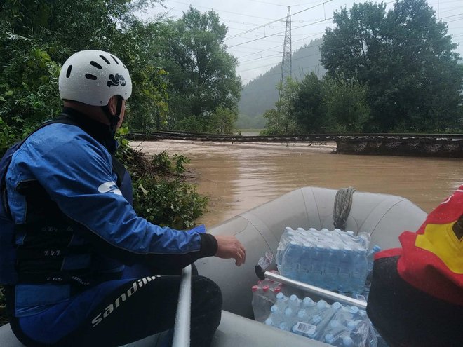 Poplavljencem mimo poškodovane proge s čolnom vozijo pomoč. FOTO: občina Litija