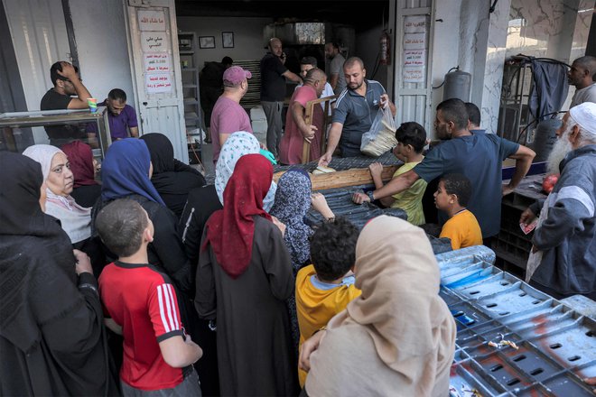 V Gazi trpijo pomanjkanje vode in hrane. Na fotografiji čakajo ljudje pred pekarno v Gazi. FOTO: Mohammed Abed/AFP