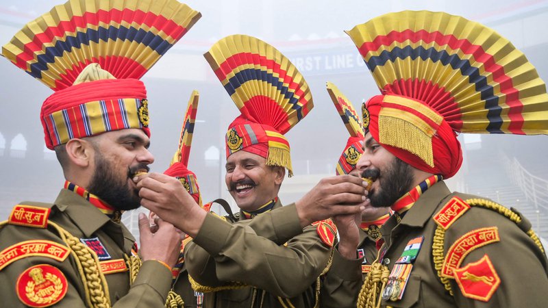 Fotografija: Vojaki indijskih obmejnih varnostnih sil (BSF) si med praznovanjem dneva republike na indijsko-pakistanskem mejnem prehodu Wagah, približno 35 km od Amritsarja, med seboj ponujajo sladkarije. Foto: Narinder Nanu/Afp