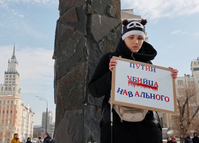 Ženska s transparentom »Putin je moriec Navalnega« na današnji fotografiji, posneti v bližini spomenika žrtvam politične represije v Moskvi. FOTO: Reuters