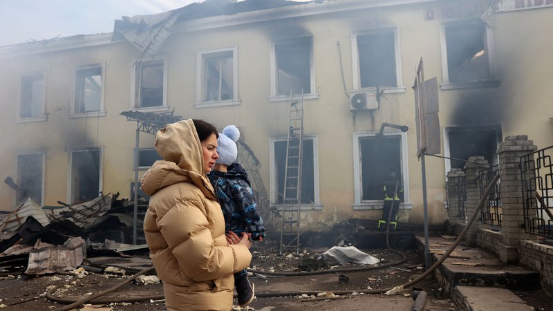 Fotografija: Ženska z otrokom hodi mimo uničene železniške postaje v Kostjantinivki, ki jo je zadela ruska raketa. FOTO: Anatolii Stepanov/Afp