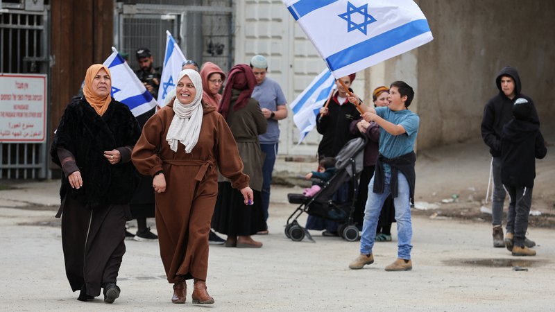 Fotografija: Muslimanske ženske in izraelski naseljenci v Hebronu. FOTO: Mussa Qawasma/Reuters