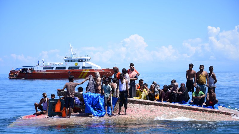 Fotografija: Rohinga begunci čakajo na rešitev iz trupa njihovega prevrnjenega čolna, ko se plovilo Nacionalne agencije za iskanje in reševanje približuje vodam približno 16 navtičnih milj od zahodnega Aceha. Indonezijske oblasti so rešile najmanj 69 beguncev, ki so bili tedne na morju in so jih 21. marca peljali na obalo, potem ko se je dan prej prevrnilo njihovo plovilo. Foto: Zahlul Akbar/Afp

 