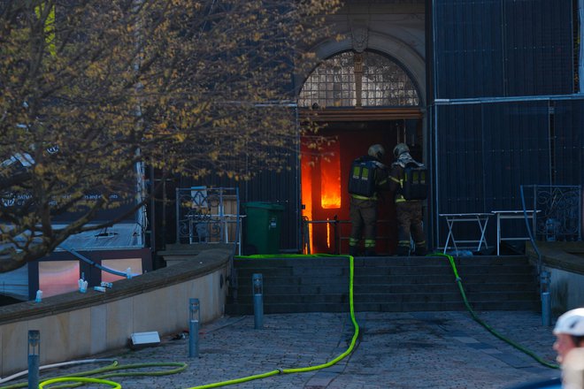 Gasilci na glavnem vhodu v gorečo zgodovinsko stavbo, postavljeno v začetku 17. stoletja na pobudo danskega kralja Kristijana IV. FOTO: Ida Marie Odgaard/AFP
