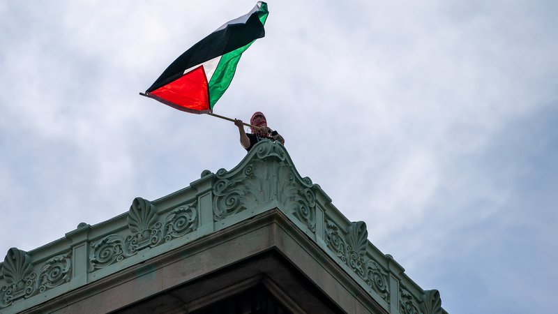 Fotografija: Protestnik s palestinsko zastavo na strahi objekta v okviru newyorške univerze Columbia. FOTO: David Dee Delgado/Reuters