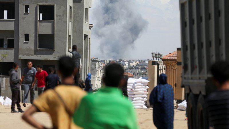 Fotografija: Ljudje opazujejo dim pred začetkom napadov izraelske vojske na Rafo. FOTO: Hatem Khaled/Reuters