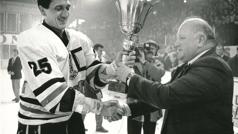 Fotografija: Drago Mlinarec je v kapetanski vlogi jeseniških hokejistov prejel pokal za prvi naslov prvakov v samostojni Sloveniji. Izročil mu ga je Janko Popovič, takrat predsednik HZS. FOTO Zoran Vogrinčič/Delo