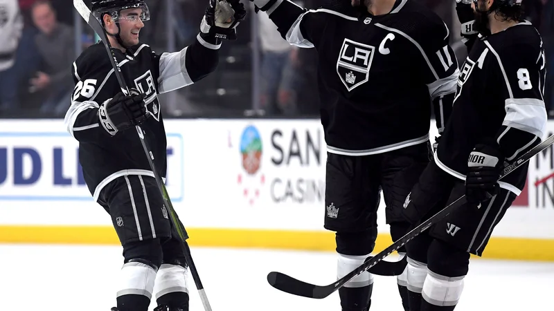 Fotografija: Sean Walker (levo) in Drew Doughty (desno) sta svojemu kapetanu Anžetu Kopitarju čestitala za prvi gol, ki je napovedal zmago Los Anglelesa proti Minesoti. FOTO: AFP