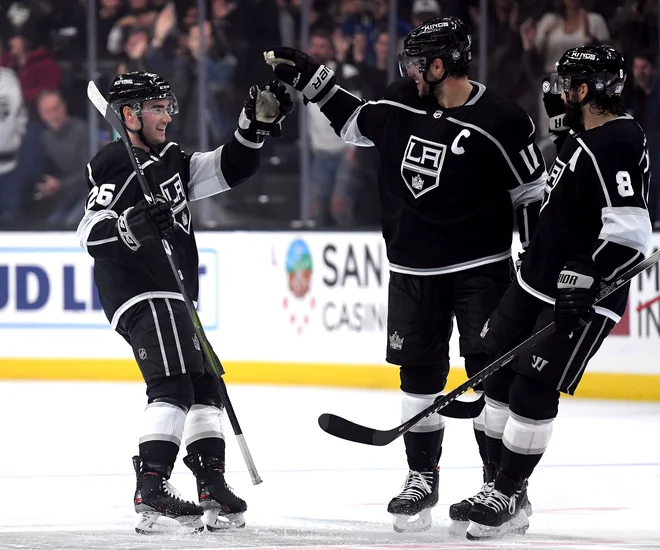 Sean Walker (levo) in Drew Doughty (desno) sta svojemu kapetanu Anžetu Kopitarju čestitala za prvi gol, ki je napovedal zmago Los Anglelesa proti Minesoti. FOTO: AFP