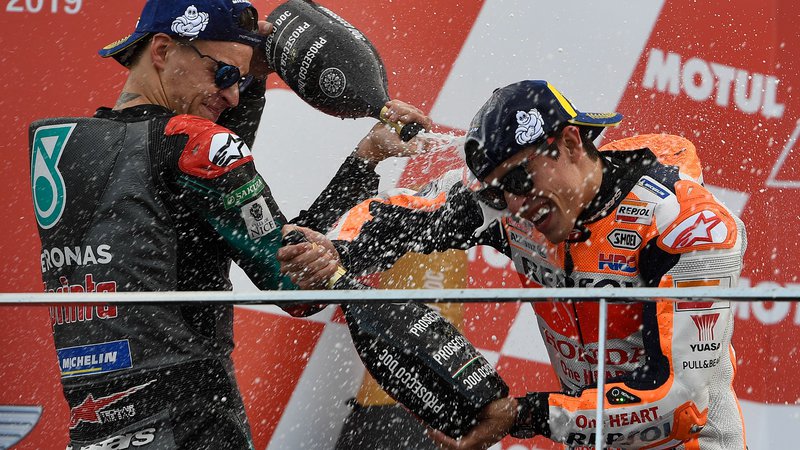 Fotografija: Vzhajajoči francoski zvezdnik Fabio Quartararo je po slovesni razglasitvi s šampanjcem poškropil Marca Marqueza, ki je z zmago na veliki nagradi Valencie le še potrdil naslov svetovnega prvaka v razredu motoGP. FOTO: AFP