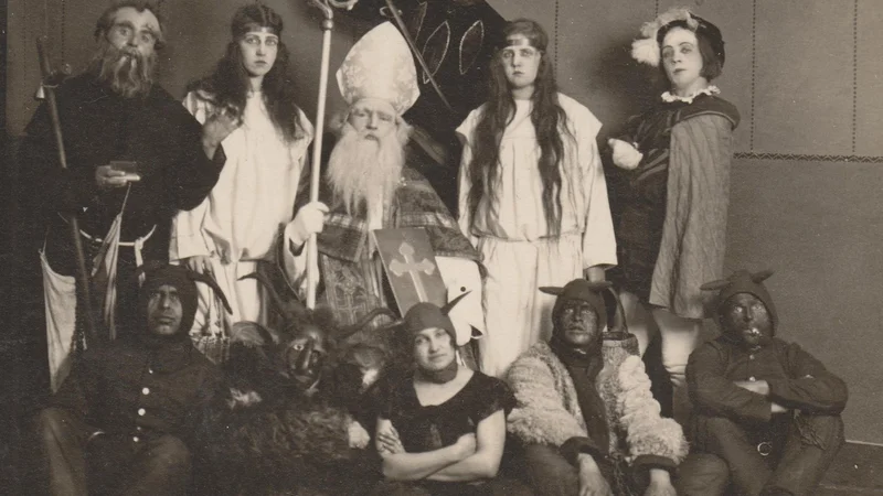 Fotografija: Miklavž s parkeljni in drugim spremstvom, Tržič, okoli leta 1930. »Moj oče je bil vedno parkelj in v ovčjo kožo oblečen, kar si je sam naredil. Ta fotografija je nastala, ko so šli k tovarnarju Molinu. Oče ga je hotel vkleniti in je z verigami tekal za njim. Miklavž pa je bil, nisem prepričana, tajnik na občini in je bil velik in ponosen gospod, imel je vilo,« se je ob tej fotografiji spominjala Ivica Žitnik. Fotografije arhiv Tržiškega muzeja