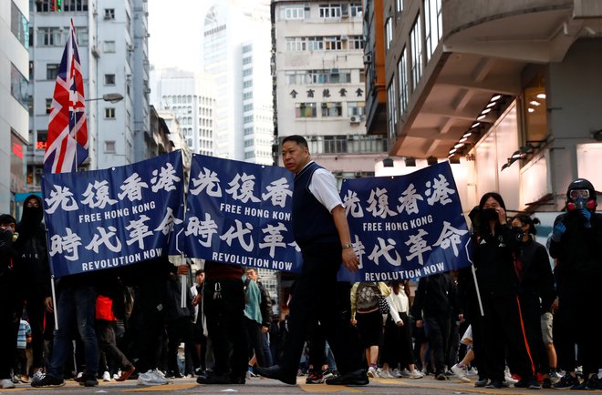 Nekateri udeleženci protestov vihtijo ameriške, tajvanske in britanske zastave. FOTO: Thomas Peter/Reuters