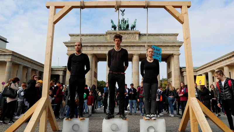 Fotografija: Aktivisti pred Brandenburškimi vrati opozarjajo na segrevanje planeta. FOTO: Fabrizio Bensch/Reuters